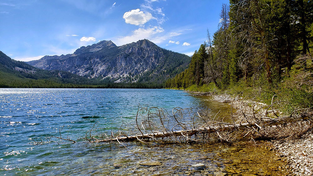 Sawtooth National Recreation Area in Idaho with clear alpine lake, forest shoreline, and mountain backdrop