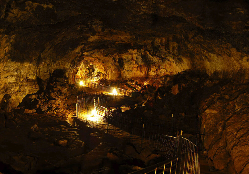 Idaho’s Mammoth Cave Lava Tube Illuminated walkway inside Idaho’s Mammoth Cave, showing lava-formed rock walls and underground passage way in southern Idaho