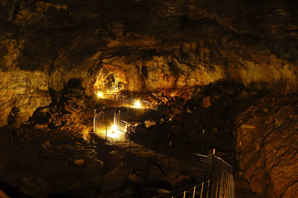 Illuminated walkway inside Idaho’s Mammoth Cave, showing lava-formed rock walls and underground passage way in southern Idaho