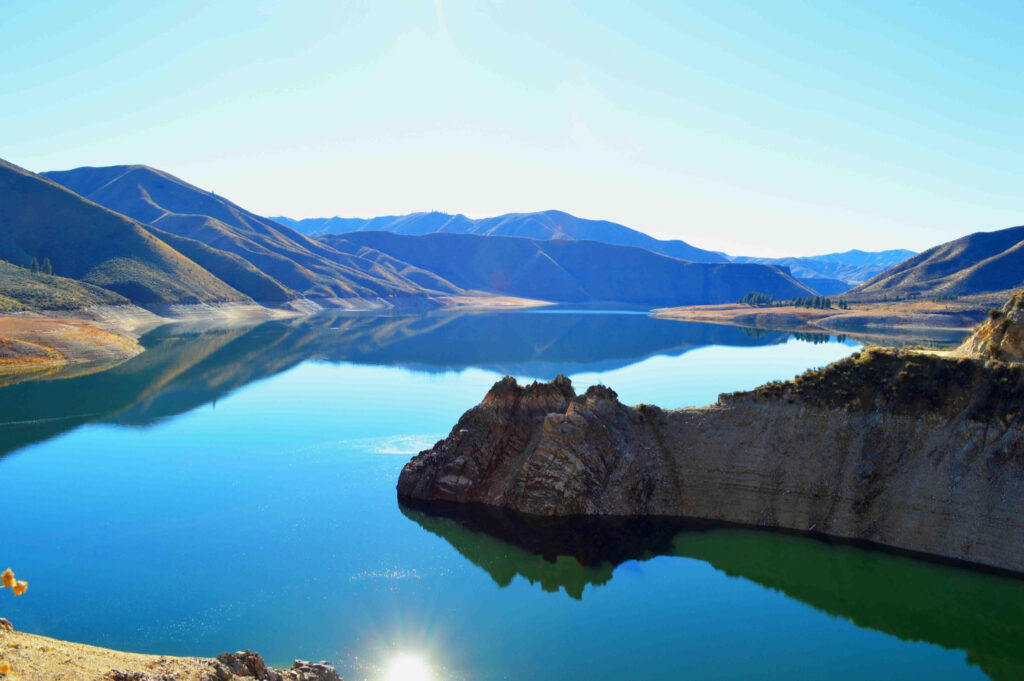 Calm reservoir near the Boise, Idaho area surrounded by rolling hills and reflective blue water on a clear day