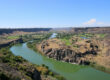 Scenic view of the Snake River Canyon in southern Idaho, showing the river winding through desert cliffs and green valley landscapes
