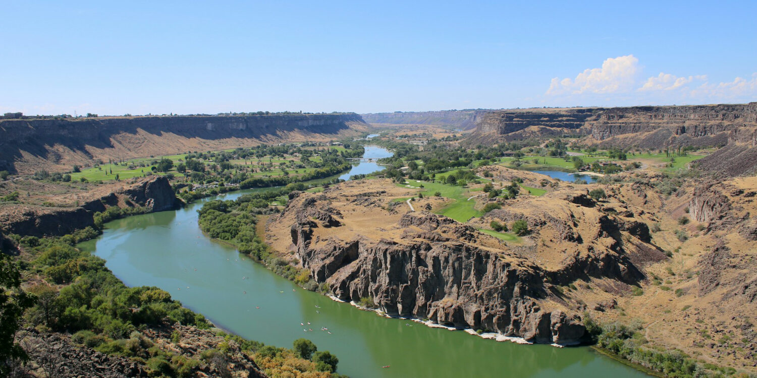 Scenic view of the Snake River Canyon in southern Idaho, showing the river winding through desert cliffs and green valley landscapes