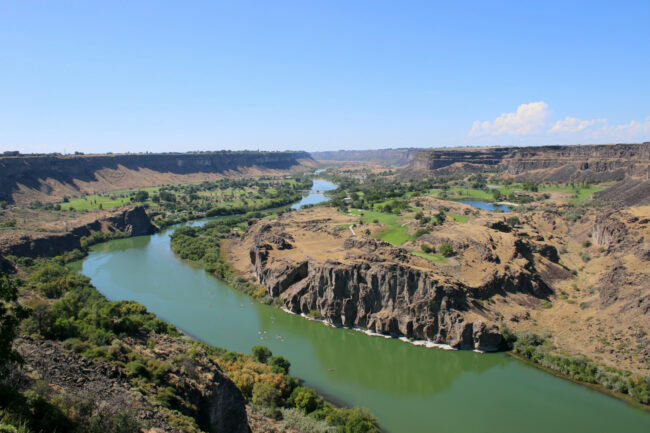 Scenic view of the Snake River Canyon in southern Idaho, showing the river winding through desert cliffs and green valley landscapes