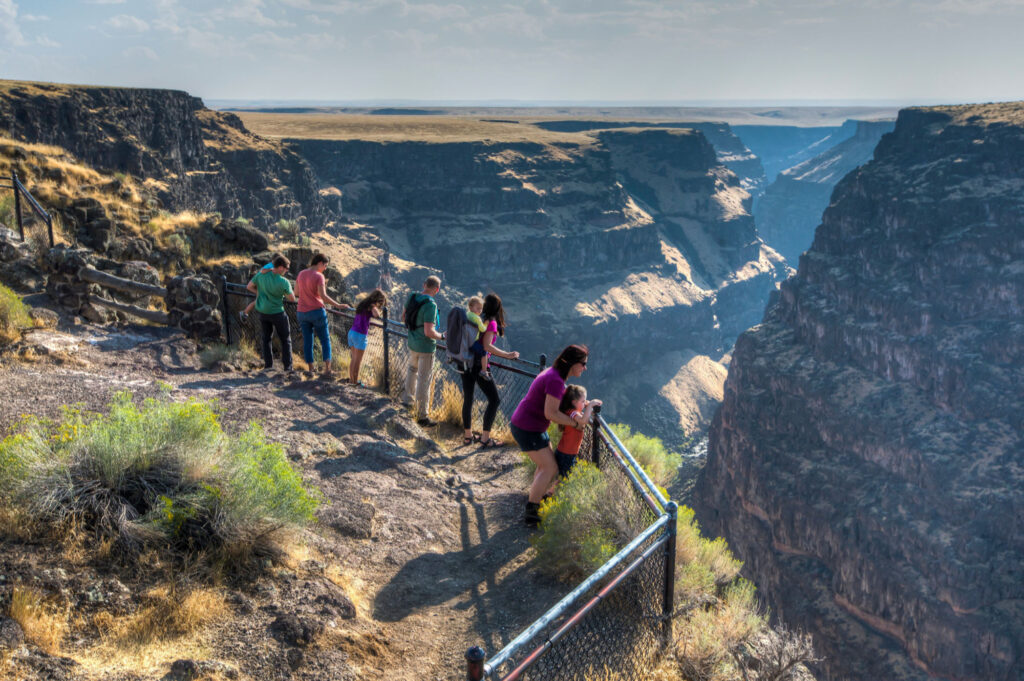 Visitors standing at Bruneau River Overlook in Southern Idaho, viewing the deep canyon landscape and scenic desert cliffs.