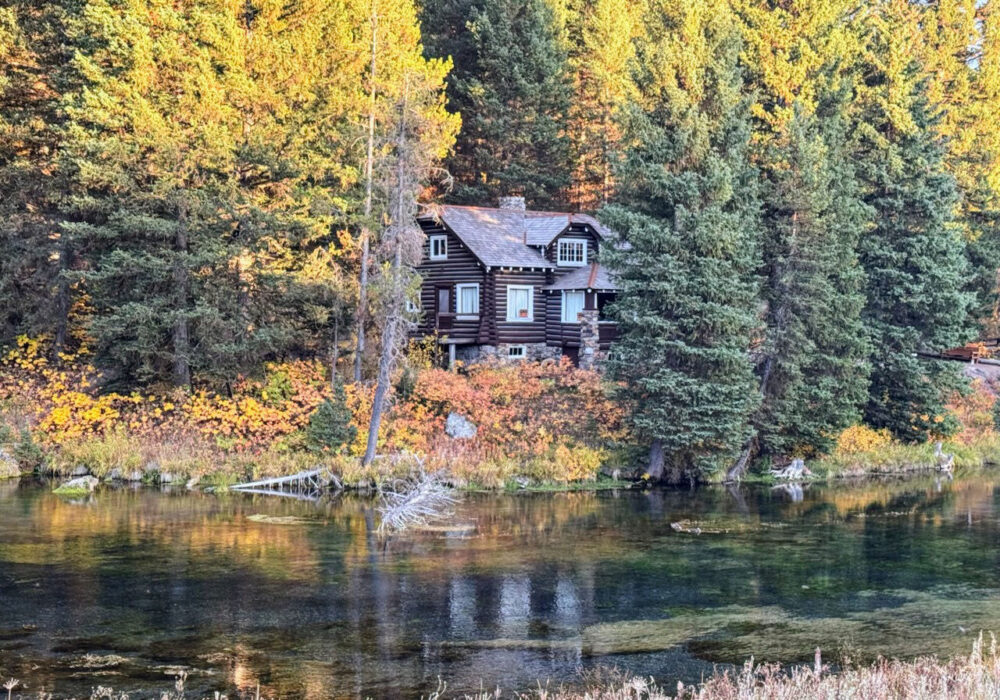 Log cabin surrounded by fall foliage along the clear waters of Big Springs in Island Park, Idaho