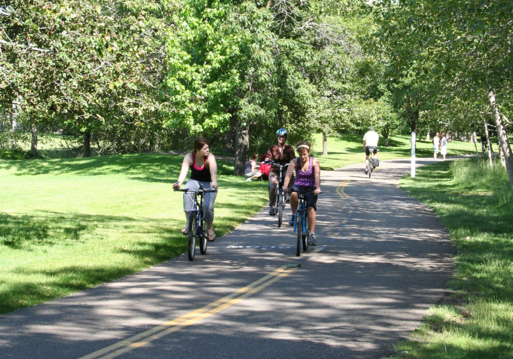 people biking along Boise River Greenbelt in Idaho on tree-lined paved path