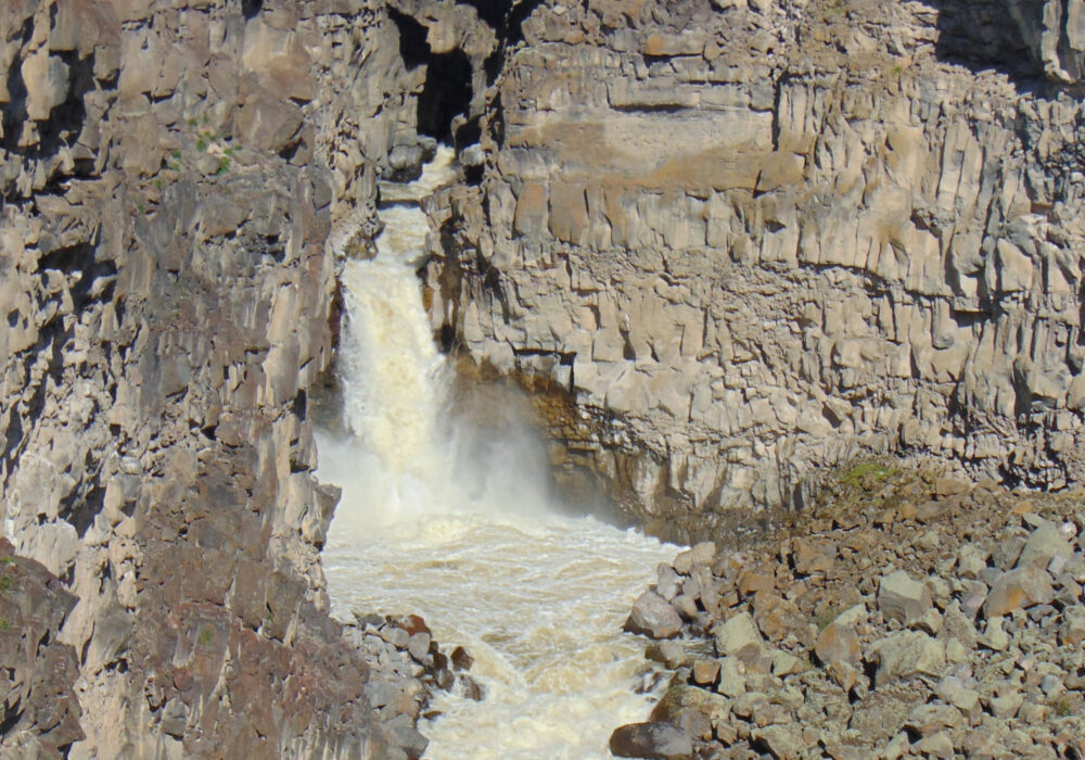 Devil’s Washbowl waterfall in Malad Gorge State Park Idaho flowing through a narrow basalt canyon beneath a bridge