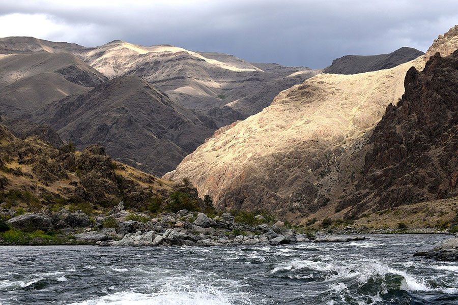 Snake River flowing through Hells Canyon in Idaho with steep rocky mountains and dramatic landscape