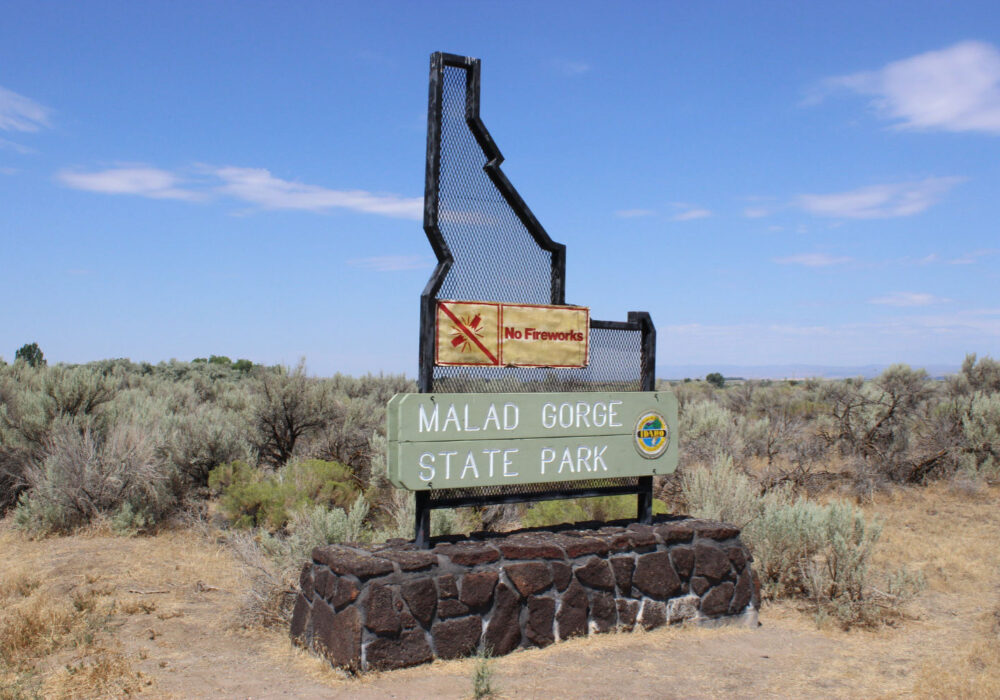 Malad Gorge State Park entrance sign surrounded by sagebrush landscape under a blue sky in southern Idaho