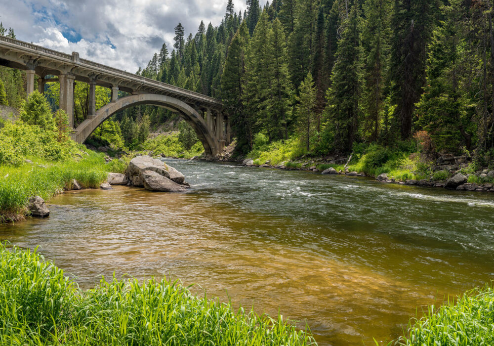 Arched bridge over the Payette River along the Banks Lowman Road in Idaho surrounded by pine forest and flowing water