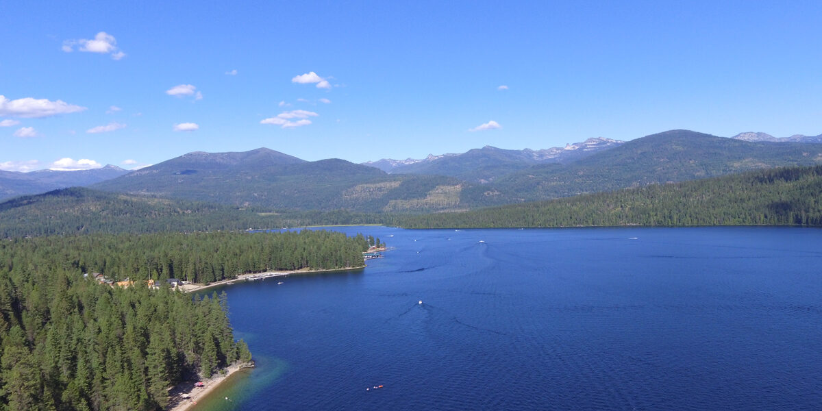 Aerial view of Priest Lake in Idaho with clear blue water, forested shoreline, and mountain scenery