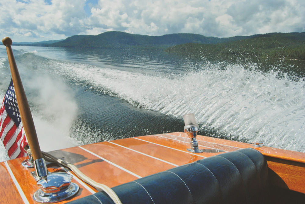 Speedboat cruising across Priest Lake in Idaho with mountain views and water wake behind the boat