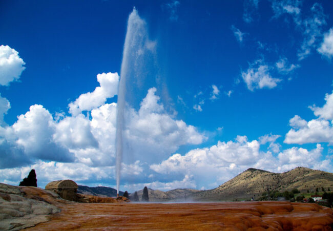 Soda Springs Geyser erupting in Idaho with wide scenic view of hills and mineral ground, one of the most unique things to do in Idaho