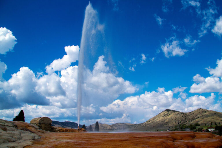 Soda Springs Geyser erupting in Idaho with wide scenic view of hills and mineral ground, one of the most unique things to do in Idaho