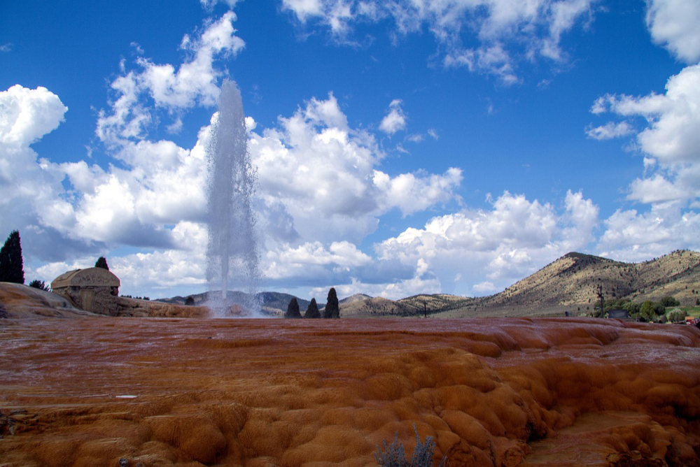 Soda Springs Geyser erupting in Idaho with surrounding hills and mineral formations, a scenic and unique attraction in Idaho