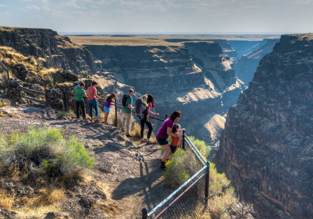 bruneau-canyon-overlook-idaho Visitors standing at the Bruneau Canyon Overlook near Bruneau, Idaho looking out across the deep canyon landscape and cliffs